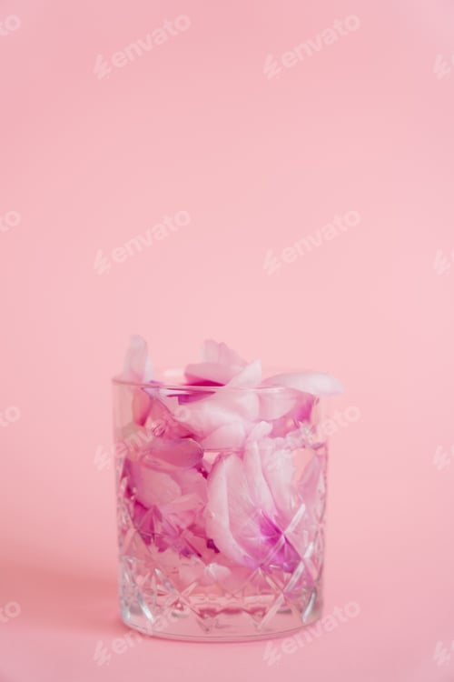 Preview: crystal glass with natural floral petals and tonic on pink background