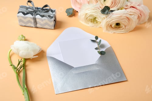 Preview: Beautiful ranunculus flowers, gift box and card in envelope on color background. Space for text
