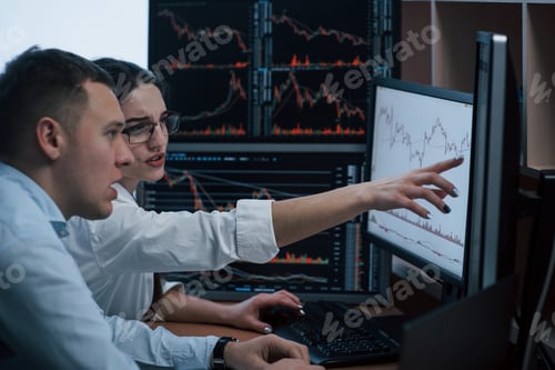Preview: Team of stockbrokers are having a conversation in a office with multiple display screens