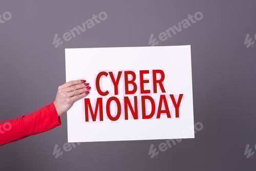 Preview: Female hand holding a cyber monday poster. Studio shot.