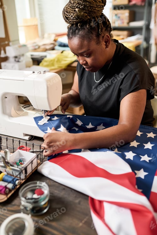 Preview: Young African American female volunteer making flag of USA in workshop