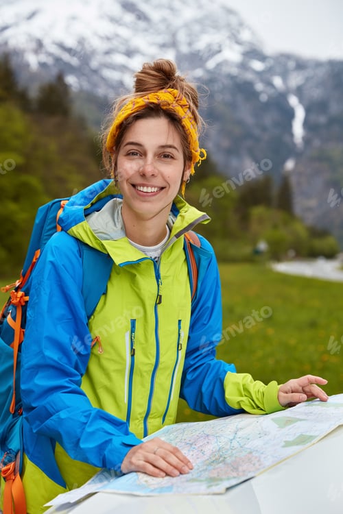 Preview: Woman hitchhiker studies map on hood of car, gets to mountains, enjoys journey adventure, wears jack