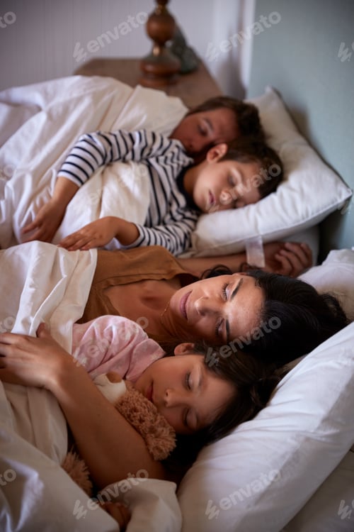 Preview: Mid adult parents and their two young children lying asleep in bed, waist up, close up, vertical