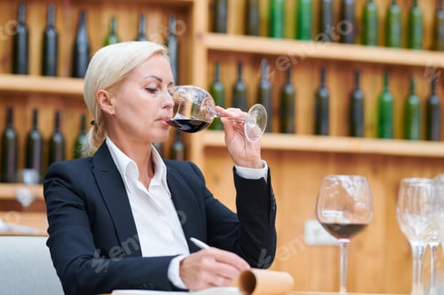 Preview: Pretty blonde woman making notes about quality and flavor of red wine