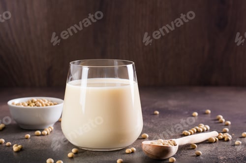 Vista previa: Leche de soja en un vaso y soja en un bol sobre la mesa. Bebida sin lactosa.
