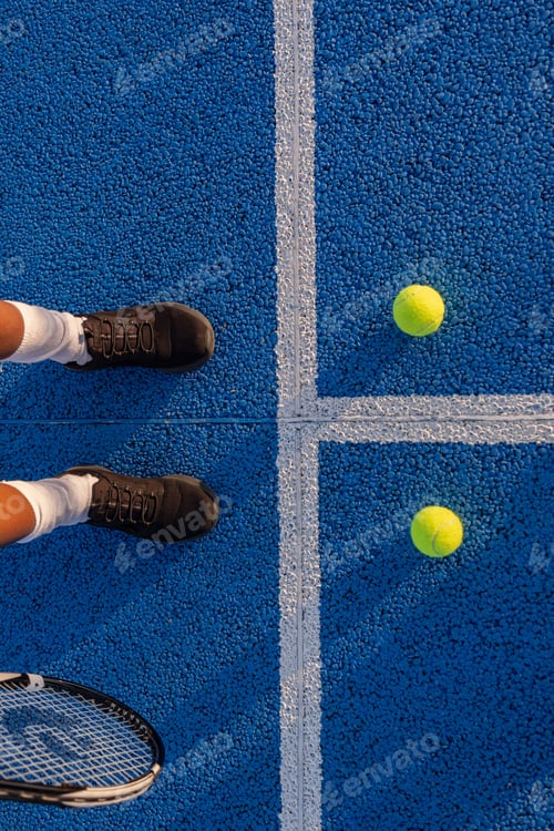 Preview: Tennis player standing on blue court with racket and balls