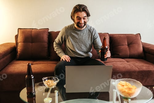 Preview: Man Relaxing at Home Video Conferencing With Beer