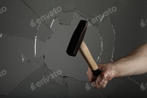 Preview: Man breaking window with hammer on grey background, closeup