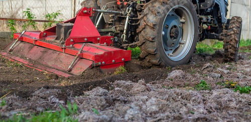 Preview: Tractor cultivating soil in the garden. Selective focus.