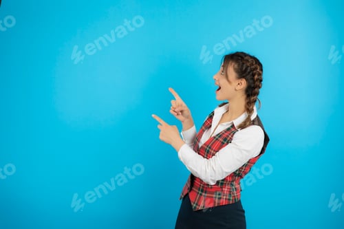 Preview: Young shocked college girl in uniform holding fingers to the left side