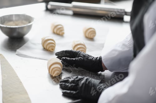 Preview: Baker arranging croissants on stainless steel table in bakery