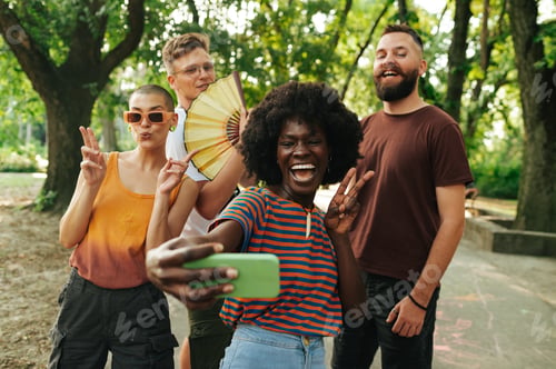 Preview: Four young people walking in park and taking a selfie together.