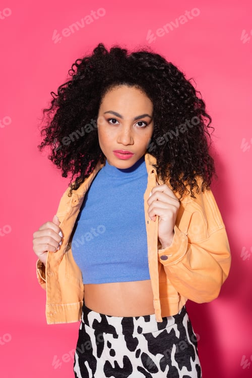 Preview: stylish african american woman in crop top and jacket on pink