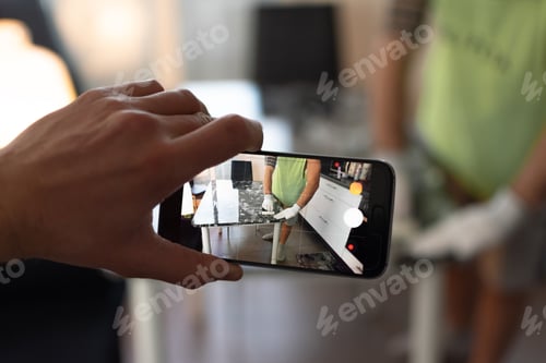 Preview: Hand holding a smartphone photographing a man renovating an old table
