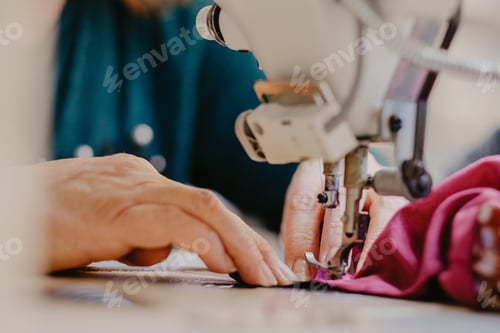 Preview: Selective focus shot of seamstress hands working on sewing machine