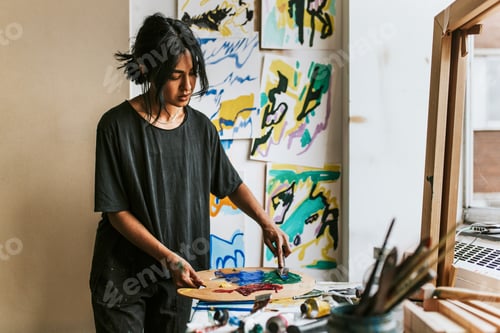 Preview: Woman artist mixing paint on a color palette