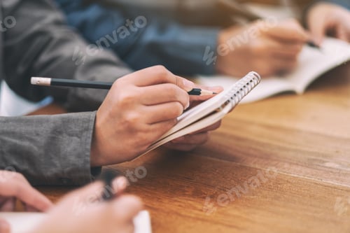 Preview: Closeup image of hands holding and writing on blank notebook on wooden table