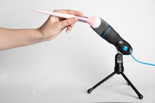 Preview: Woman making ASMR sounds with microphone and brush on grey background, closeup
