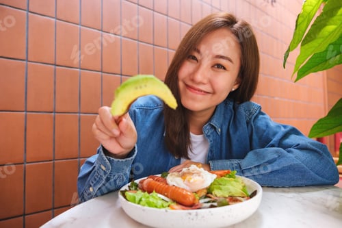 Preview: Portrait image of a young woman eating avocado and salad