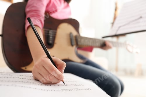 Preview: Child with guitar writing music notes at home, closeup