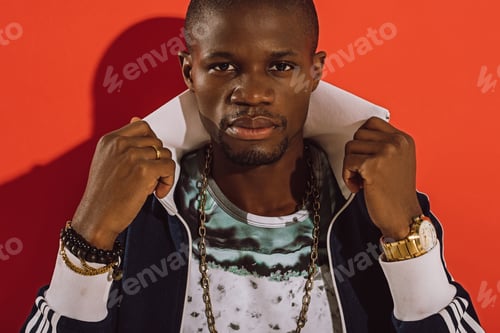Preview: stylish young african american man adjusting jacket and looking at camera