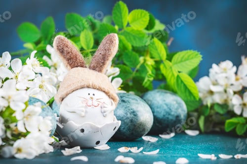 Preview: Easter rabbit figurine, blue painted eggs, white cherry flowers with leaves on blue background