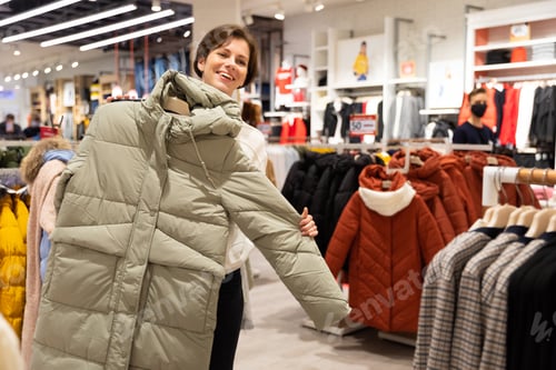 Preview: Photo of young attractive brunette woman with a short haircut in a white sweater chooses stylish and