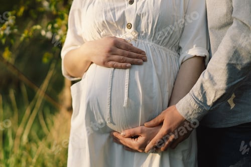 Preview: Young beautiful couple hugging in the spring garden. Concept pregnancy