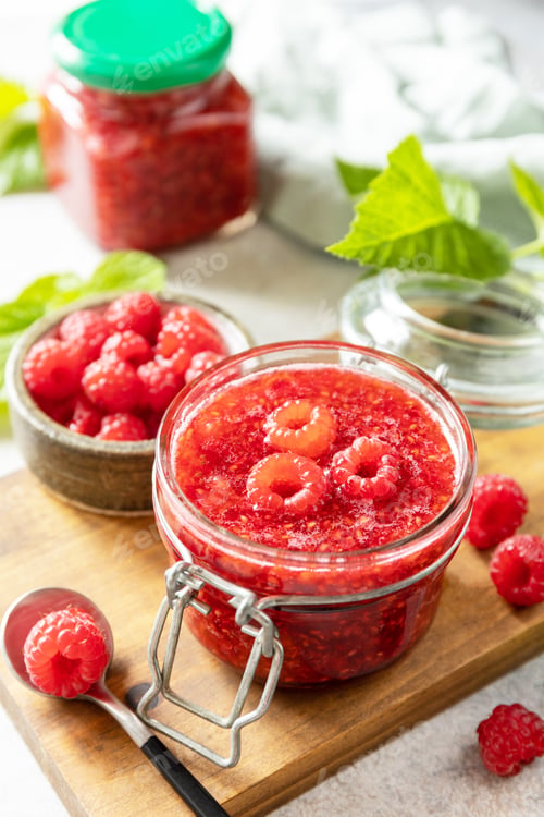 Preview: Delicious raspberries jam or jelly and fresh raspberries on a stone table. Homemade preservation.