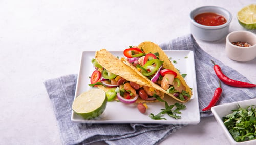Preview: two Mexican tacos with chicken, onions, chili peppers, corn and beans on a serving plate