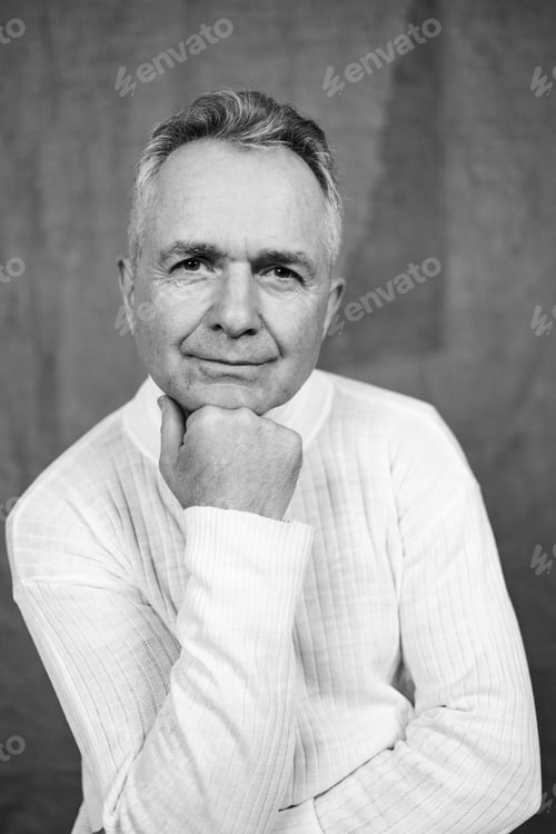 Preview: Portrait of handsome Caucasian senior man with grey hair against gray background in black and white