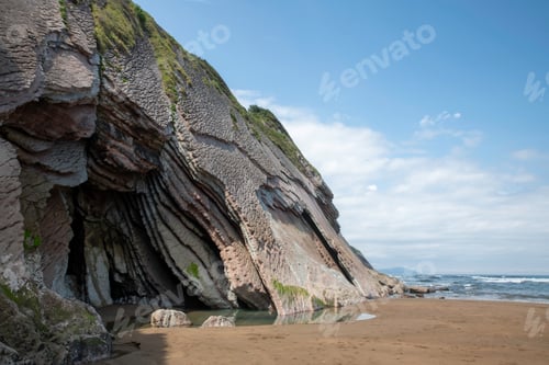 Preview: Majestic Coastal Cliff With Layered Rock Forms Over a Sandy Beach by the Sea
