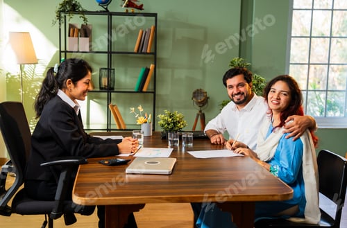 Preview: Indian married young couple signing documents with executive lady in cozy office at meeting