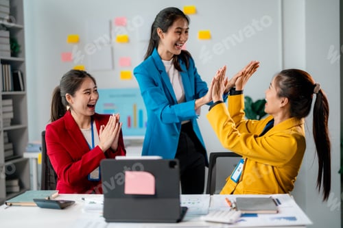 Preview: Excited businesswomen celebrating successful project in office meeting