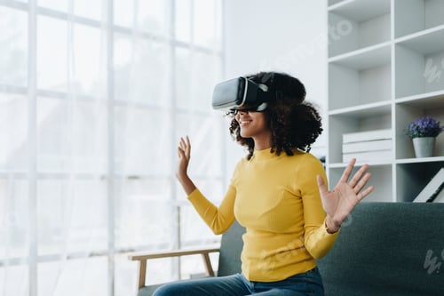 Preview: Positive African American woman teenager in futuristic VR helmet laughing and relaxing. Youthful gir