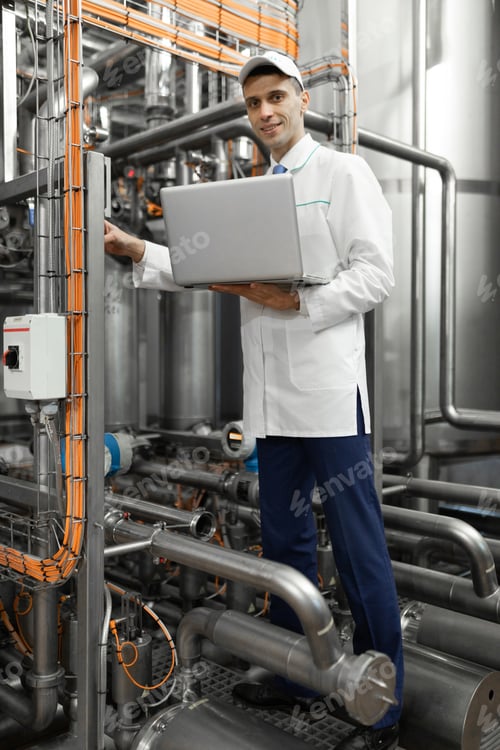 Preview: man in a white robe with a laptop in his hands among the chrome pipes