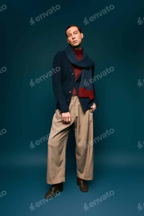 Preview: Stylish young man poses confidently against a rich blue backdrop showcasing modern fashion trends