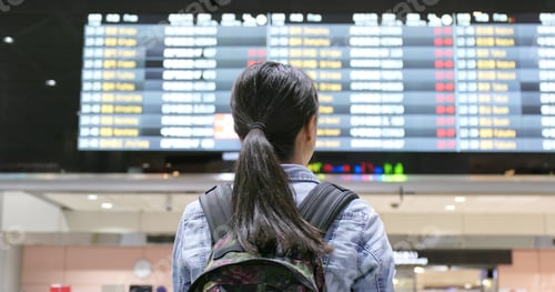 Preview: Young woman traveler looking for the flight number number at airport