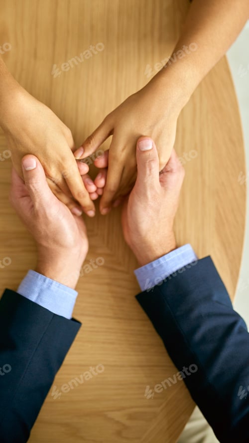 Preview: Cropped shot of a businessman and businesswoman compassionately holding hands at a table