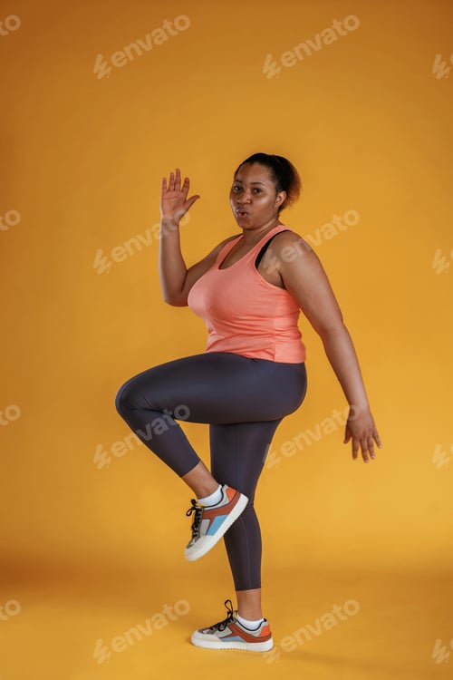 Preview: Doing fitness. African American woman is in the studio against yellow background