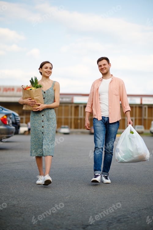 Preview: Young couple with bags on supermarket parking
