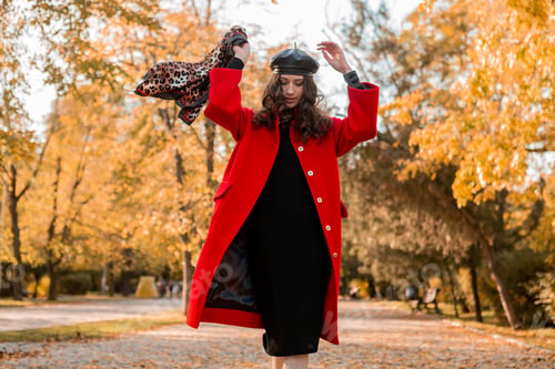 Preview: attractive stylish woman walking in park dressed in warm red coat