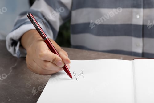 Preview: Writer signing autograph in book at table, closeup