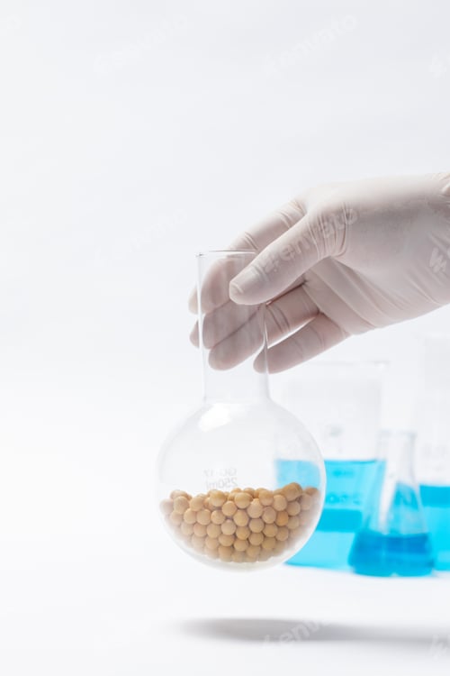 Preview: Vertical shot of a scientist holding chickpeas in a flask against a white background