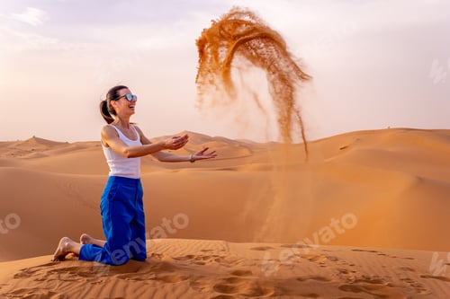 Preview: Woman playing with sand in the desert.