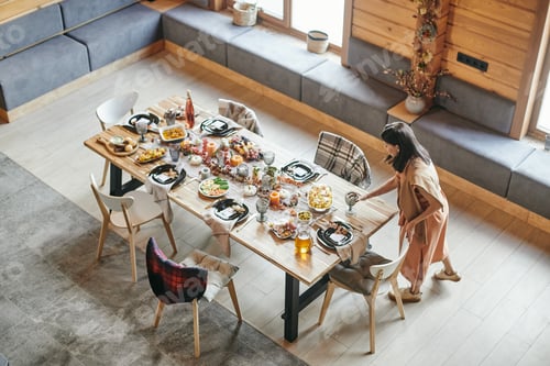 Preview: Young brunette woman putting glass on served festive table
