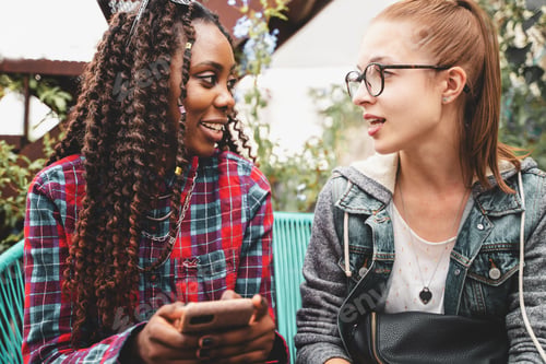 Preview: Multiracial happy girls sitting outdoors in the terrace talking together