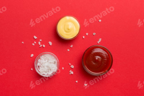 Preview: Bowl of salt, ketchup and cheese sauce on colored background, top view with copy space