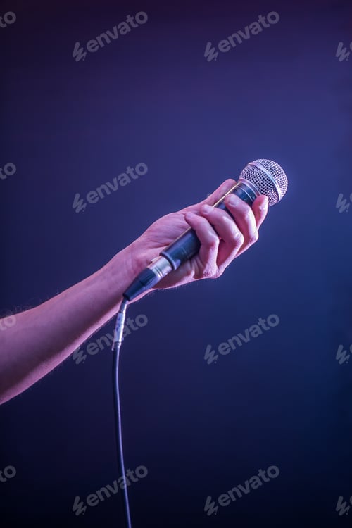 Preview: hand with microphone on a black background, the music concept, beautiful lighting on the stage