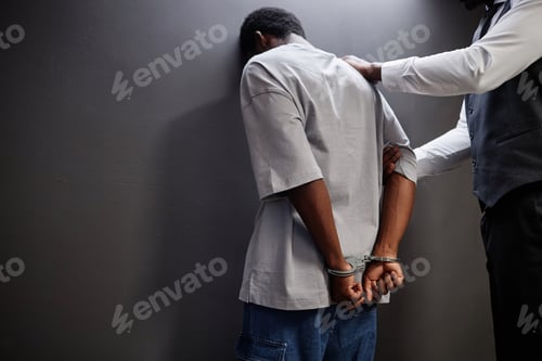 Preview: Man arrested standing by wall with officer putting on handcuffs